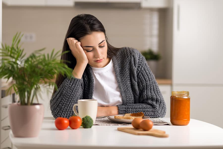 Young woman looking at food not feeling hungry