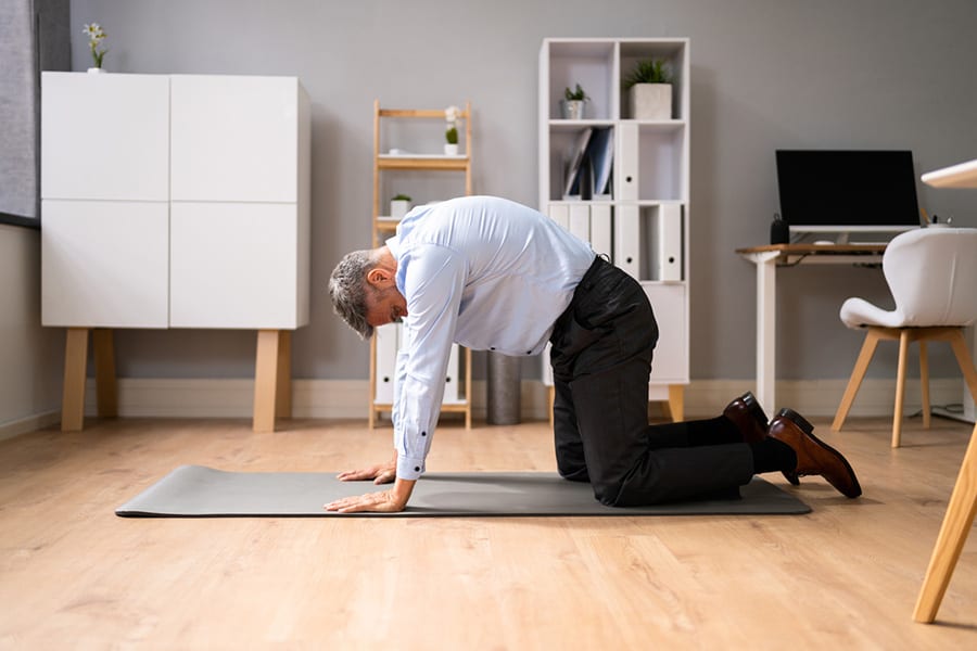 A middle aged man doing yoga poses at home to relieve back pain or to fix bad posture