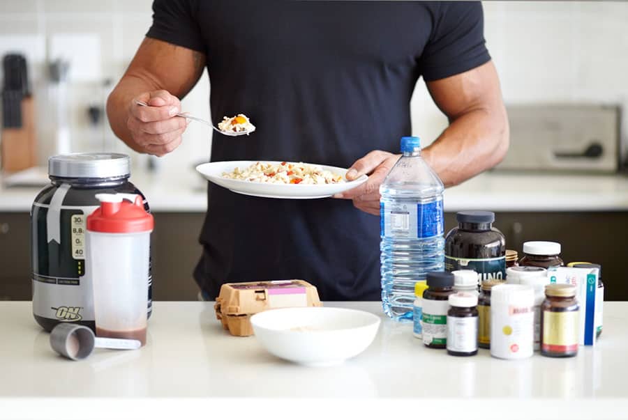 A fit man with a breakfast plate, and a lot of workout supplements