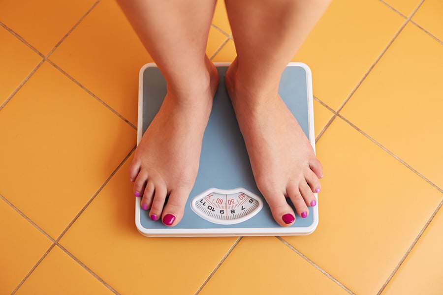 Woman checking her weight on a weighing machine