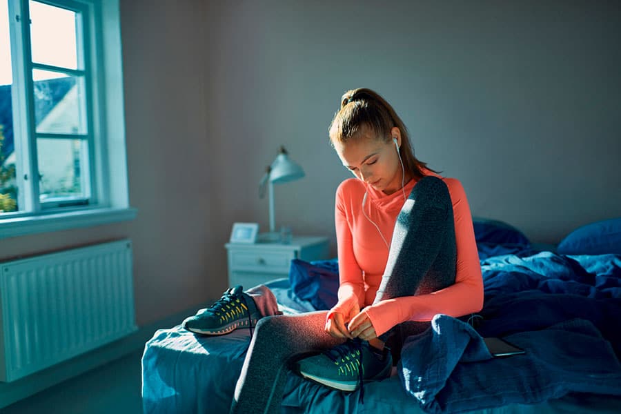 Woman tying laces of her workout shoes in preparation for fitness training