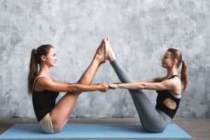 Two women performing boat asana yoga together