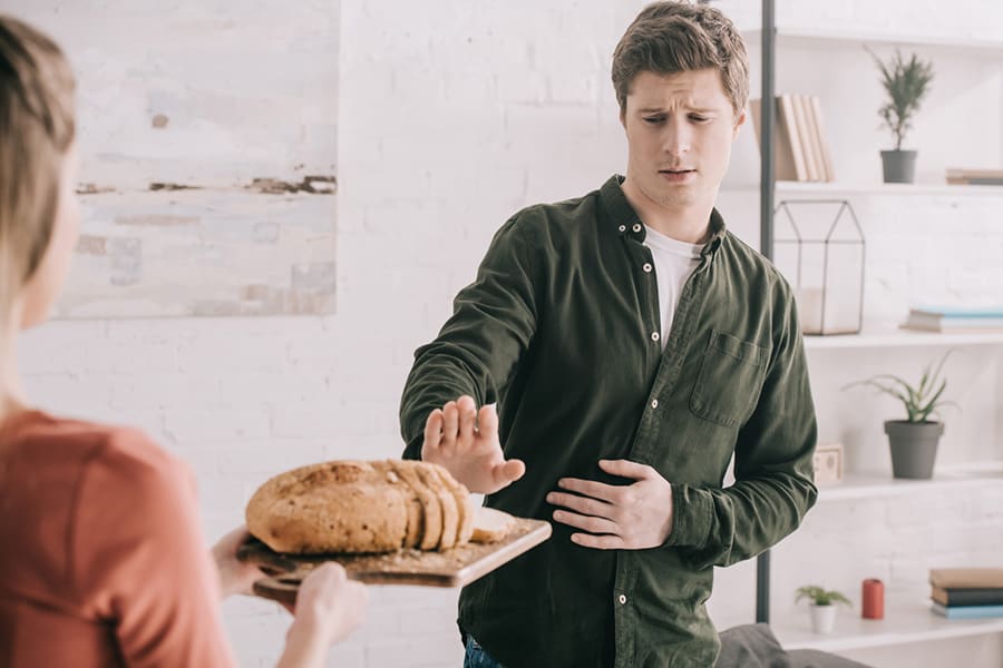 Man trying to avoid eating sliced bread due to a gluten-free allergy