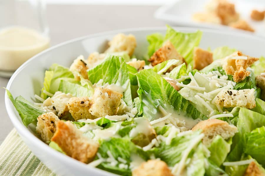 A bowl full of caesar salad placed on a table