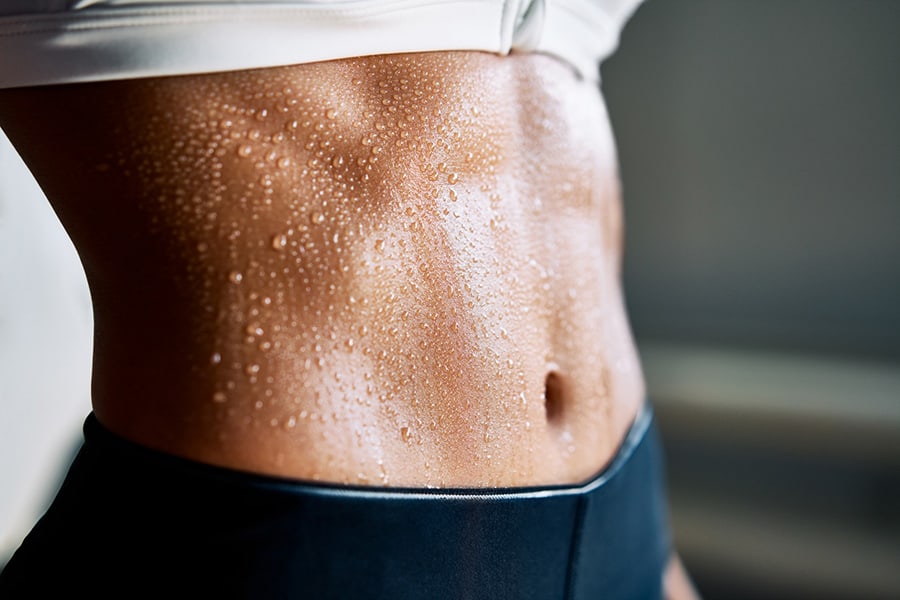 Close up of fit woman torso with sweat on skin after workout