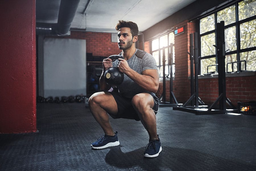 A fit man performing goblet squats in a gym