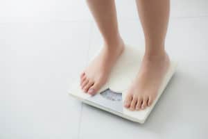 A teenager is weighing himself/herself on a weighing machine