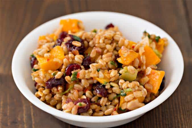 A bowl of farro cooked with pumpkin, cranberries, and herbs.
