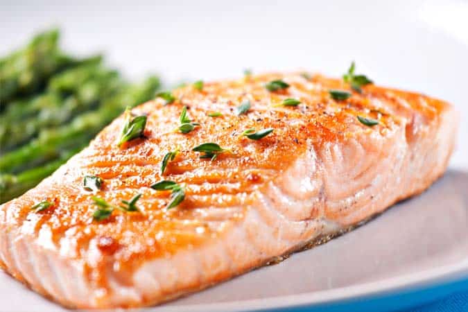 A slice of cooked salmon sprinkled with herbs.