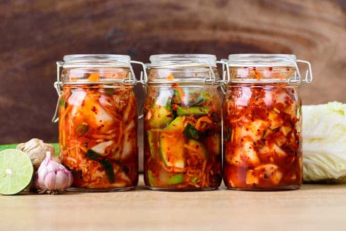 Three airtight glass jars filled with pickled vegetables.