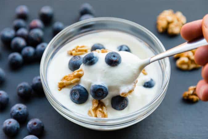 A bowl of Greek yogurt with blueberries and walnuts.