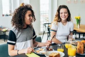 2 teenagers are enjoying their breakfast