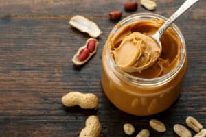 A spoonful of peanut butter being taken out of a jar.