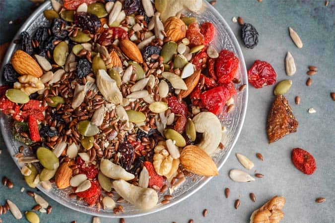 A trail mix of nuts and seeds and dried fruits: almonds, cashews, walnuts, chia seeds, pumpkin seeds, watermelon seeds, black raisins, figs, and cranberries