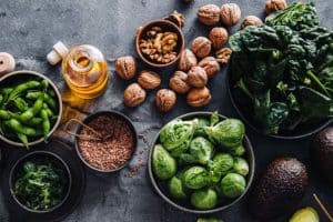 Omega 3 vegan foods like walnut, brussels sprouts, edamame, flax seeds and more are placed on a table.