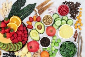 Vegan anti-inflammatory diet foods like strawberry, avocado, apple, pomegranate, cucumber and many more are on a table.