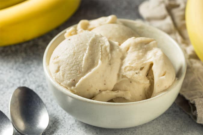 Scoops of vegan banana ice-cream served in a white bowl.