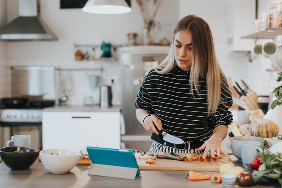 A girl is trying to cook in kitchen by watching a video