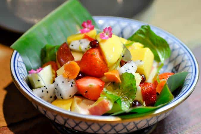 A bowl of fruit salad with chunks of strawberry, dragon fruit, and mango.