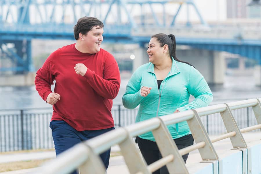 A fat couple is running happily to achieve their goal of losing belly fat.