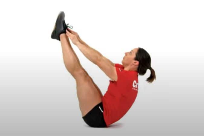 A fitness enthusiast performs v-sit-ups.