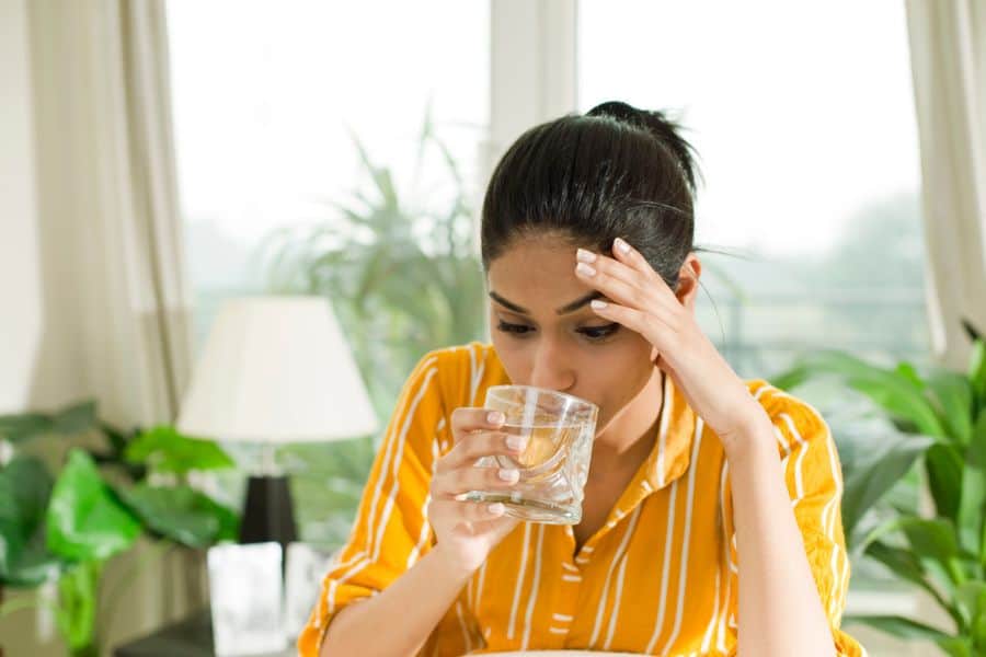 A young lady is drinking a glass of water.